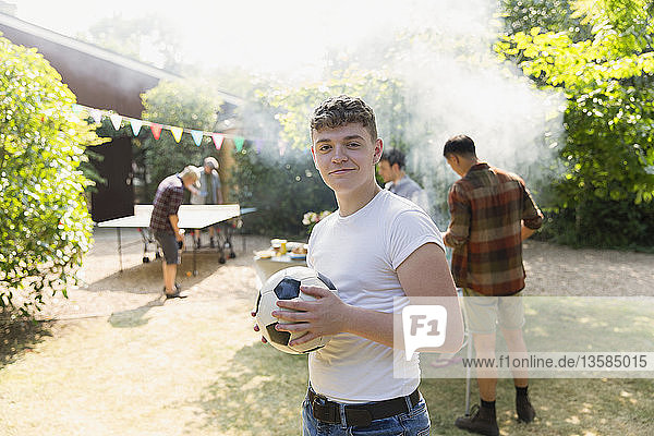 Porträt selbstbewusster Jugendlicher mit Fußball  der im Hinterhof grillt