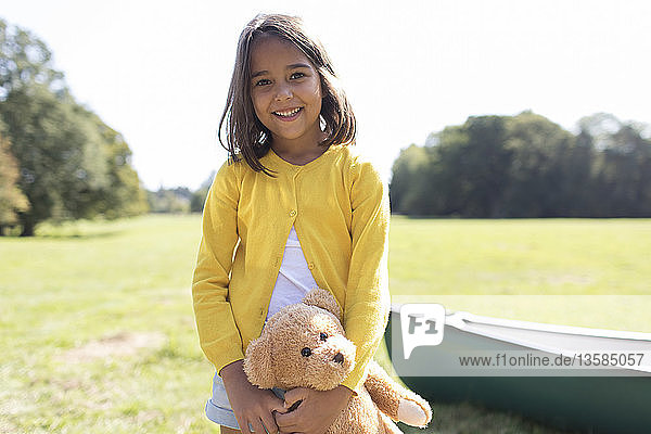 Portrait smiling cute girl with teddy bear in sunny field