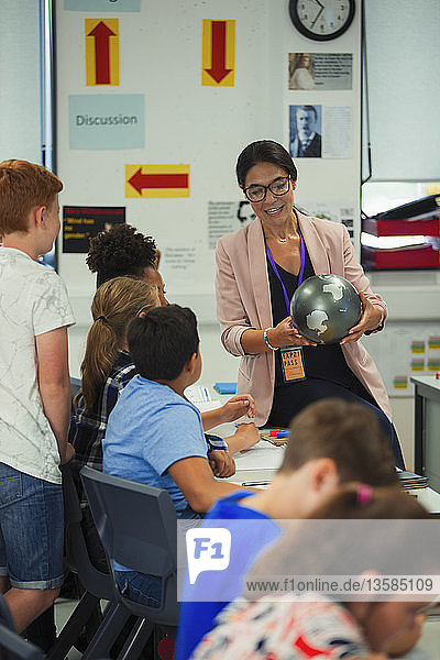 Geografielehrerin mit Globus beim Unterricht im Klassenzimmer