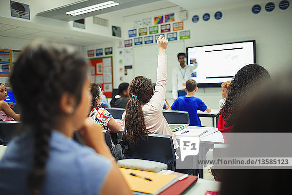 Junior high school student raising hand  asking a question during lesson in classroom
