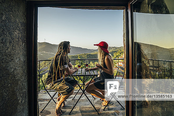 Couple relaxing  drinking wine on sunny balcony