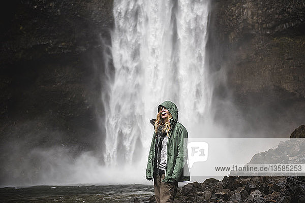 Smiling female hiker in rain jacket at waterfall  Whistler  British Columbia  Canada