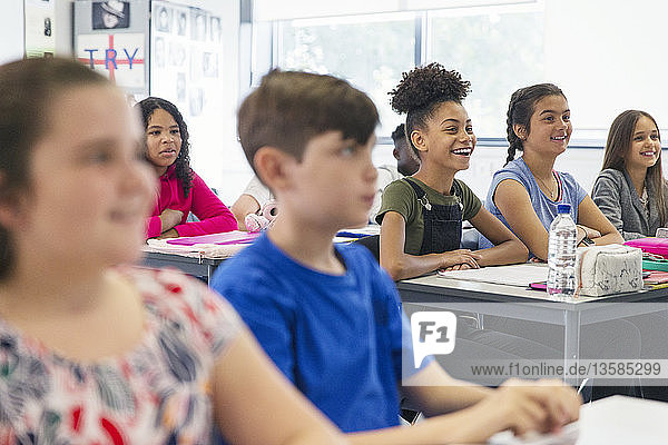 Lächelnde Schüler der Junior High School hören im Unterricht zu