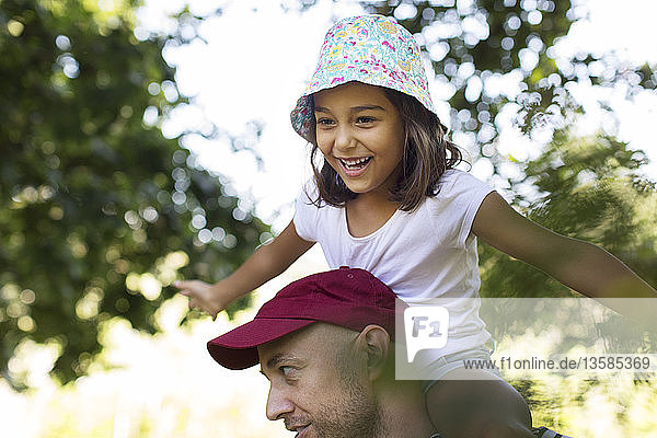 Happy carefree girl on father’s shoulders