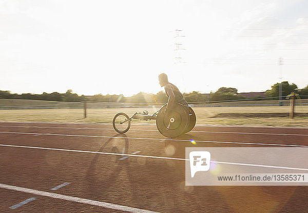 Junger querschnittsgelähmter Sportler beim Training für ein Rollstuhlrennen auf einer sonnigen Sportbahn