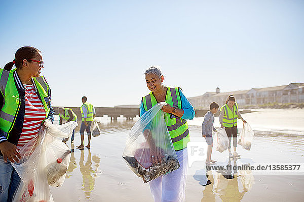 Volunteers cleaning up litter on sunny  wet sand beach