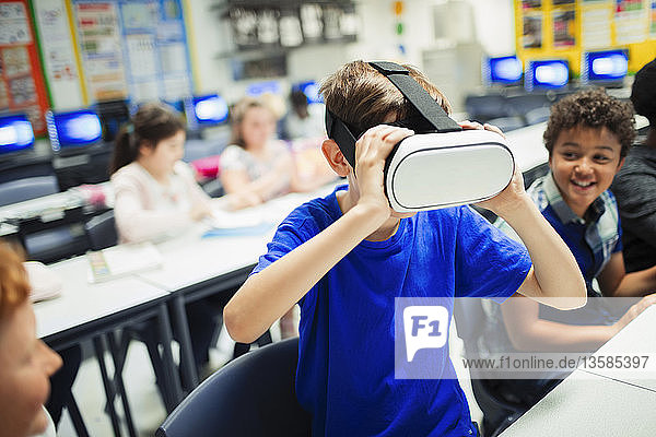 Junior high school boy student using virtual reality simulator glasses in classroom
