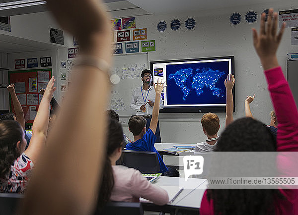 Schüler der Junior High School  die mit erhobenen Händen im Klassenzimmer teilnehmen