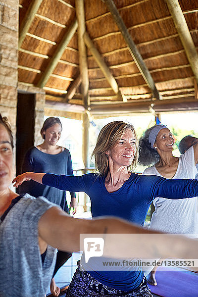 Confident woman practicing warrior 2 pose in hut during yoga retreat