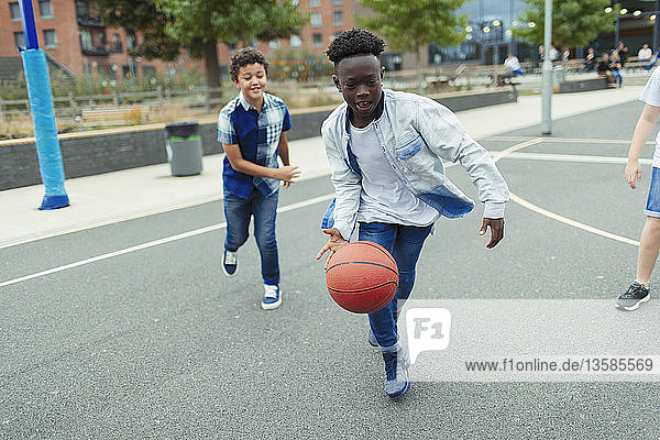 Tween boys playing basketball in schoolyard