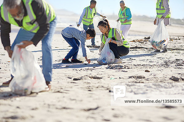 Mutter und Sohn beseitigen freiwillig Müll am sonnigen Sandstrand