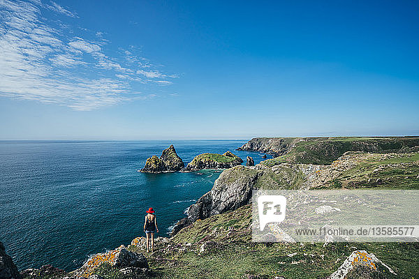 Frau steht auf sonnigen Klippen mit Blick auf das Meer  Cornwall  UK