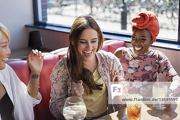Happy  excited young women drinking cocktails in restaurant