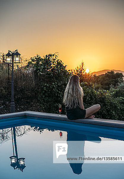 Frau entspannt sich mit Wein und genießt den Sonnenuntergang am ruhigen Pool  Aveiro  Portugal