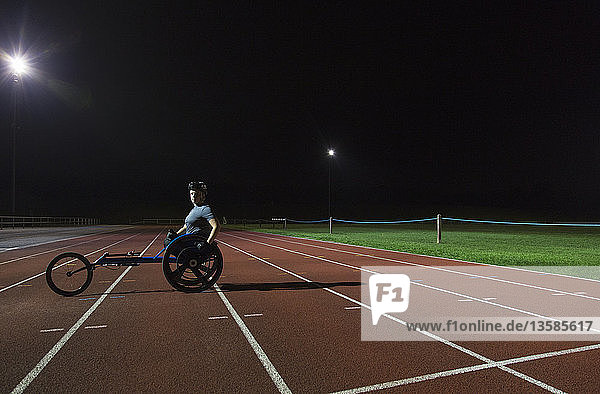 Portrait confident young female paraplegic athlete training for wheelchair race on sports track