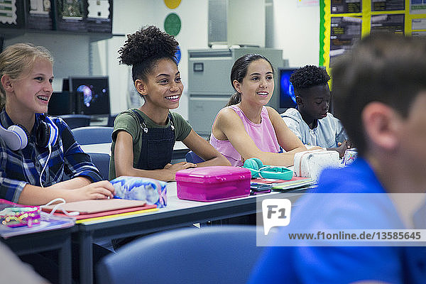 Lächelnde Junior High School Mädchen Studenten am Schreibtisch im Klassenzimmer