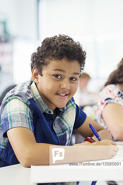 Portrait confident elementary age boy doing homework in classroom