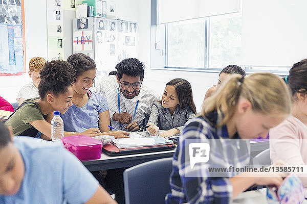 Lehrerin hilft Schülern der Junior High School am Schreibtisch im Klassenzimmer