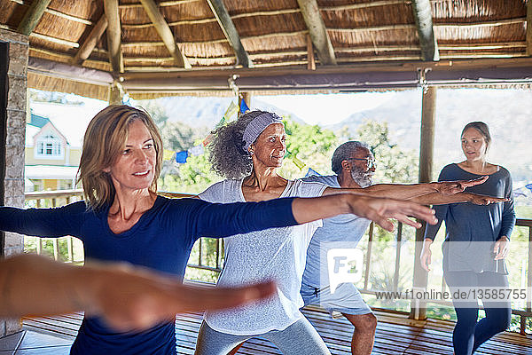 Yogaklasse beim Üben der 2-Krieger-Pose in einer Hütte während eines Yoga-Retreats