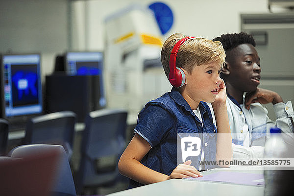 Konzentrierter Junge der Junior High School mit Kopfhörern im Klassenzimmer
