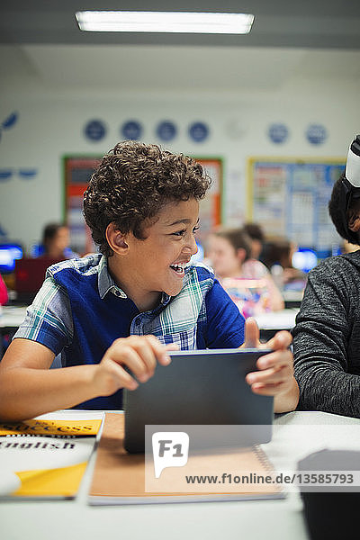 Happy elementary school boy using digital tablet in classroom