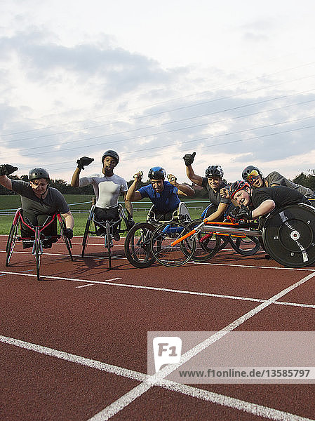 Porträt begeisterter querschnittsgelähmter Sportler  die für ein Rollstuhlrennen auf einer Sportbahn trainieren und dabei jubeln