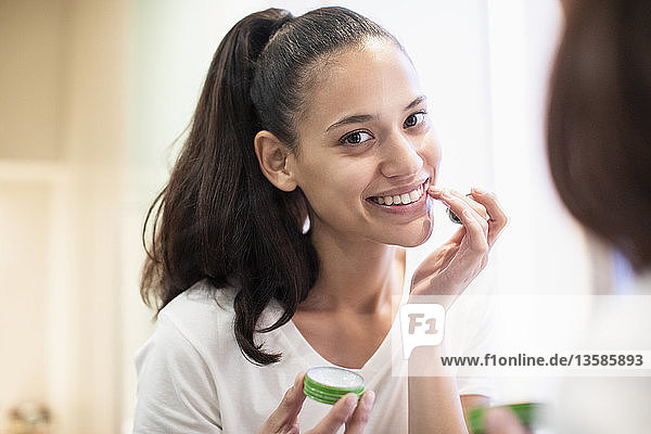 Portrait smiling  confident woman applying lip balm in bathroom mirror