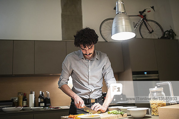Mann schneidet Gemüse  kocht Abendessen in der Wohnküche