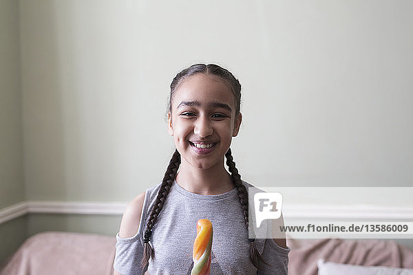 Porträt eines lächelnden  selbstbewussten Mädchens  das aromatisiertes Eis isst