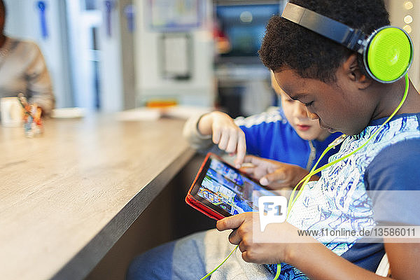 Junge mit Kopfhörern und digitalem Tablet  der ein Videospiel spielt