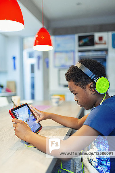 Junge mit Kopfhörern und digitalem Tablet  der ein Videospiel spielt