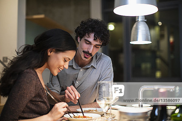 Ehepaar isst Abendessen mit Stäbchen in der Wohnküche