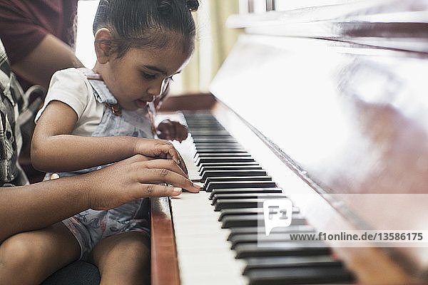 Curious toddler girl playing piano