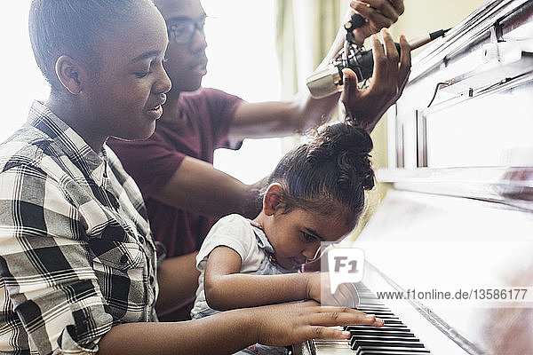 Bruder und Schwestern spielen Klavier