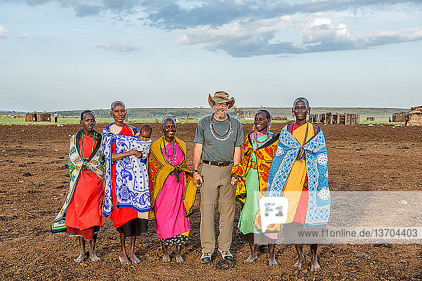 Local Maasai women greet and hold hands with photographer and visitor,  Jim Steinberg,  at their village at Maasai Mara National Reserve in Kenya,  Africa.