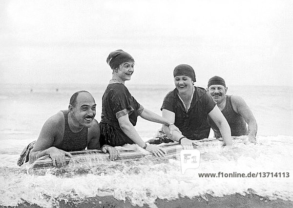 Palm Beach  Florida: um 1918 Die in Palm Beach überwinternde Gesellschaft  Harry Hoy aus New York  Annah Slattery aus Providence und Mr. und Mrs. Edward P. Kennedy aus Boston  erfreuen sich am neuesten Strandspaß in Florida: der schwimmenden Matratze.