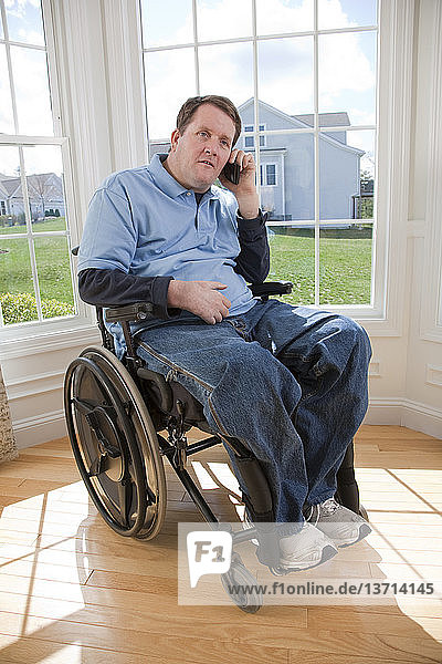 Mann mit Rückenmarksverletzung im Rollstuhl spricht mit einem Mobiltelefon