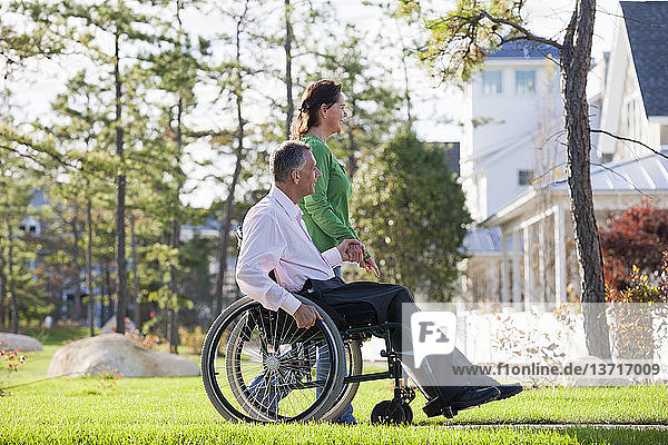 Ehepaar schaut sich ihre Nachbarschaft an  während er mit einer Rückenmarksverletzung im Rollstuhl sitzt