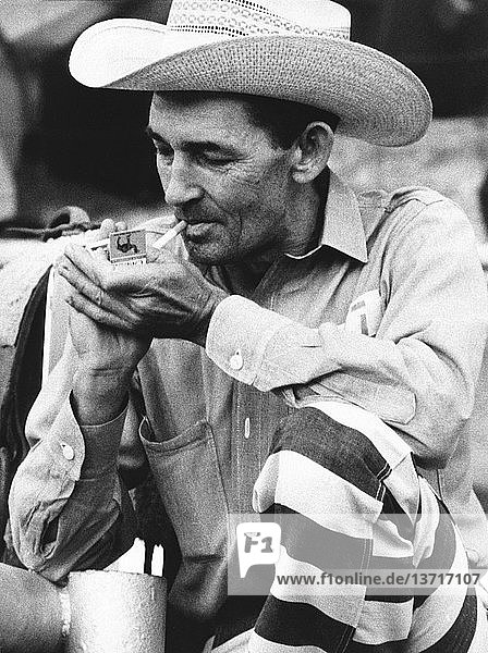 McAlester  Oklahoma: September. 1971 Ein gefangener Cowboy  der am Gefängnisrodeo teilnimmt  zündet sich eine Camel-Zigarette an. Er sagt  er sei schon neunmal im Gefängnis gewesen und man habe ihm vorgeworfen  nur wegen des Rodeos zurückgekommen zu sein.