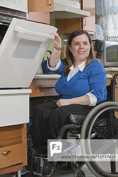 Woman with Spina Bifida in a wheelchair using a stove in the accessible kitchen