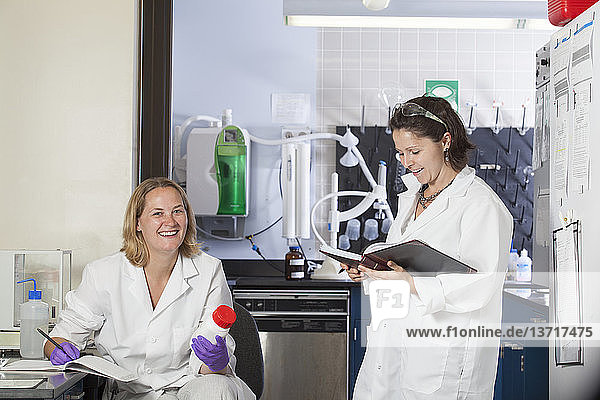 Two laboratory scientists recording chemical analysis data in a laboratory