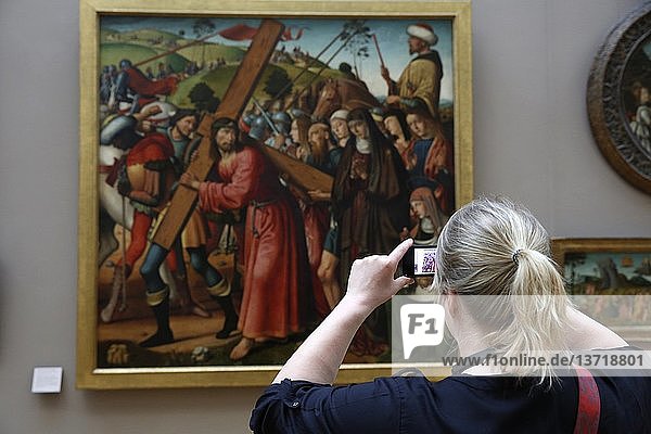 Tourist fotografiert ein religiöses Gemälde im Louvre-Museum in Paris.