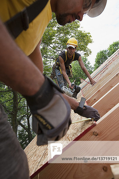 Spanische Zimmerleute beim Messen und Nageln von Dachplatten in einem im Bau befindlichen Haus