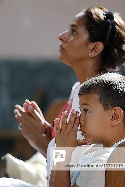 Mutter und Sohn beten in einer Kirche.