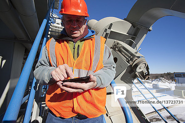 Engineer texting status on a mobile phone at materials plant in winter