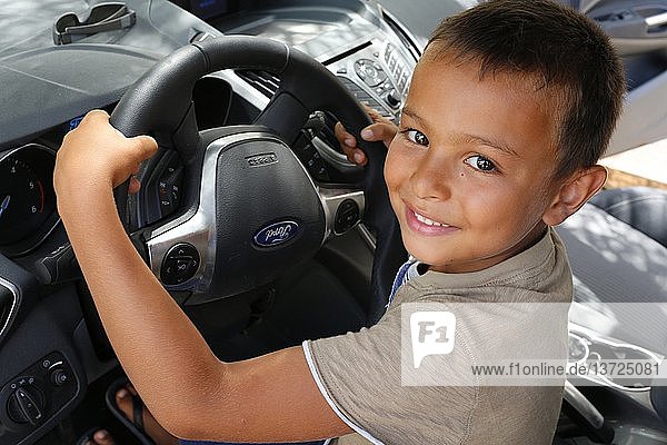 6-year-old boy pretending to drive a car.