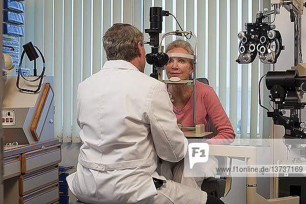 Augenarzt untersucht die Augen einer Frau mit einer Spaltlampe