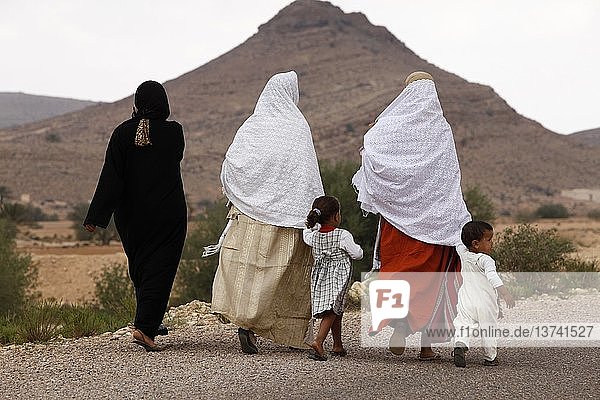 Frauen und Kinder in einem Dorf gehen auf einer Landstraße  Tunesien.