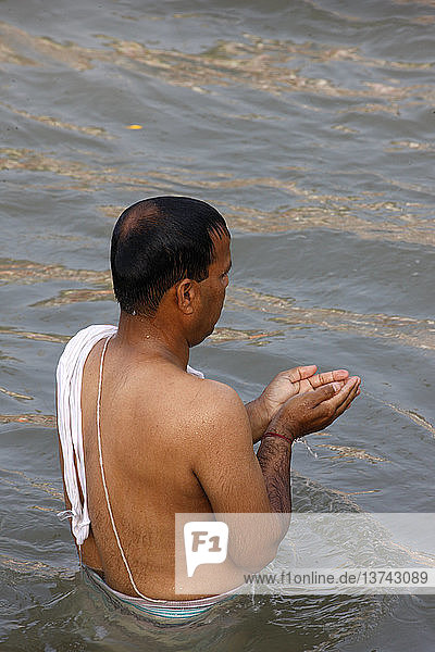 Hinduistischer Gläubiger  der anlässlich des Tages von Lord Rama im Fluss Ganges badet und betet; ein hinduistischer Feiertag  der während des Maha Kumbh Mela-Festes stattfindet '