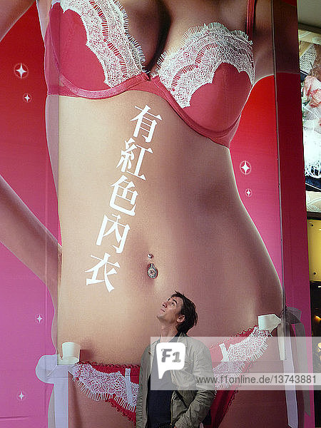 Chinesischer Mann  der sich eine Anzeige für Unterwäsche ansieht